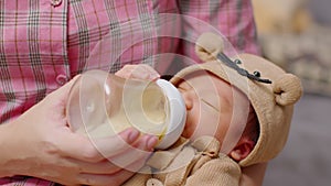 Newborn baby drinking milk from bottle on mom arms.Beautiful Asian mother holding infant baby feeding milk with love at home.