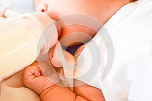 Newborn baby eating milk from the bottle.