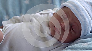 Newborn Baby Face Portrait Early Days in Macro Waking Up And Open Eyes On Blue Star Background. Child At Start Minutes
