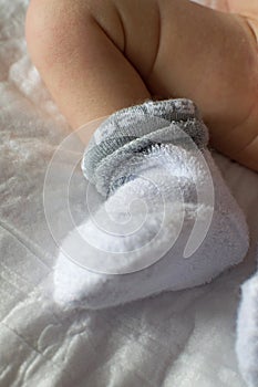 Newborn baby feet close up. Baby feet in white terry socks, baby lying on bed, baby`s legs, Newborn