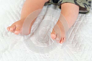 Newborn baby feet on creamy blanket, closup of infant barefeet on white background. Maternity, family, birth concept