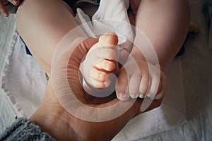 Newborn baby feet in hand of his mother