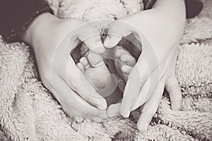 Newborn baby feet with hands of his brother