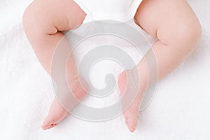 Newborn baby feet and legs on white bed background