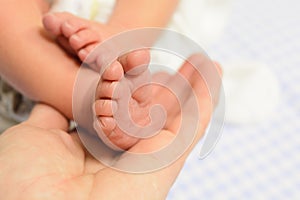 Newborn baby feet in man hand with blue background photo