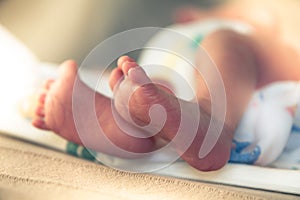 Newborn baby feet in maternity hospital with illuminating sunlight