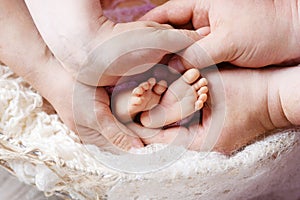 Newborn baby feet in mother and father hands. Parents holding legs of the kid in hands. Close up image.  Beautiful conceptual