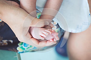 Newborn baby feet on mother hand