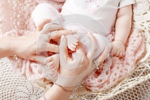 Newborn baby feet in mother hands. Mother holding legs of the kid in hands. Close up image.