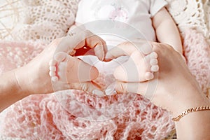 Newborn baby feet in mother hands, shape like a lovely heart. Mo