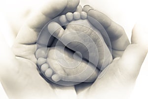 Newborn baby feet in mother hands symbolize care and parent love in black and white color