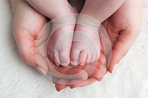 Newborn baby feet in mother's hands. Child care, feeling safe, protect.