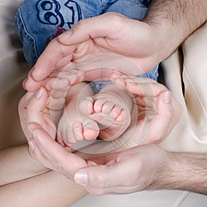 Newborn baby feet parents holding in hands.Mom and Dad hold baby legs.