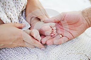 Newborn baby feet parents holding in hands. New born kind and Love symbol as heart sign