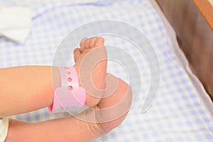 Newborn baby feet with tag. Maternity hospital. Blue nappy background with copy space photo