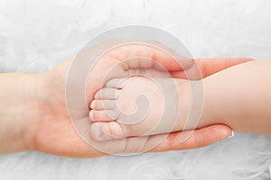 Newborn baby foot in mother's hand. Child care, love, protection