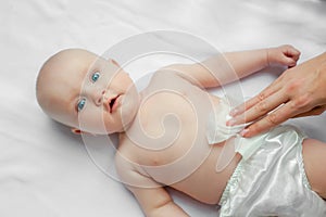 Newborn baby getting a diaper change: mom wiping baby`s bottom with baby wipe on white background. concept cleaning wipe, pure,