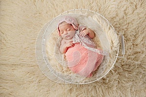 Newborn Baby Girl in Basket Wearing a Pink Bonnet
