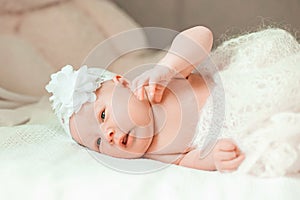 Newborn baby girl in a beautiful bonnet lying on a blanket.