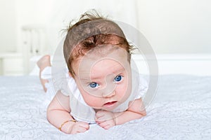 Newborn baby girl with big blue eyes on her tummy