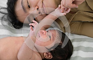 Newborn baby girl or boy lying on bed and play with mothers hands