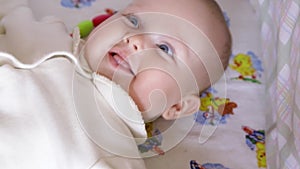 Newborn baby girl boy making funny faces smiling and stretching while waking up in own little bed