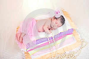 Newborn baby girl in a crown sleeping on the bed of mattresses. Fairy Princess and the Pea