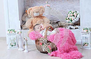 Newborn baby girl in pink blanket lying in basket