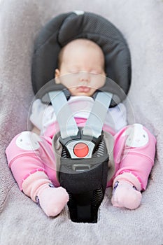 Newborn baby girl sitting in a car seat