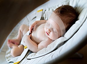 Newborn baby girl sleeping in bouncer chair