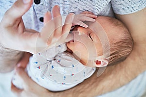 Newborn baby girl sleeping on her father`s chest