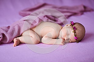 Newborn baby girl sleeping on pink background.