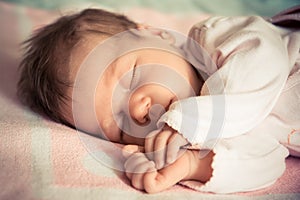 Newborn baby girl sleeping on soft blanket with natural light