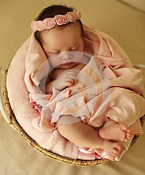 Newborn baby girl sleeping under cozy blanket in basket