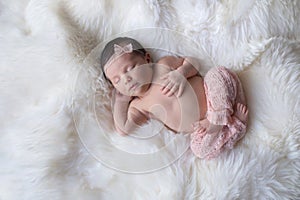 Newborn Baby Girl Sleeping on White Sheepskin Rug