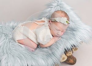 Newborn baby girl sleeps on small wooden crib.