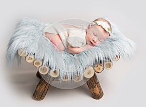 Newborn baby girl sleeps on small wooden crib.