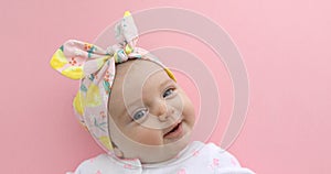 Newborn baby girl smiling pink background