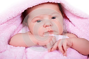 Newborn baby girl on a soft pink terry towel