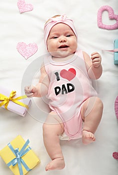 Newborn baby girl in t-shirt with inscription i love dad looking at camera. Valentine`s day