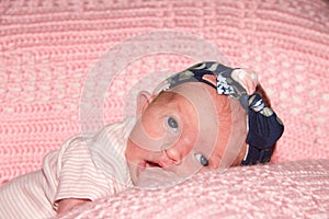 Newborn baby girl on tummy with hand in mouth