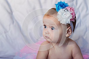 Newborn baby girl wearing a white crocheted crown, ballerina tutu, and ballet slippers. She is sleeping on pink rose