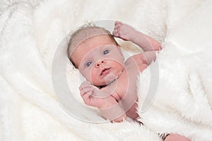 Newborn baby girl on white fluffy coverlet