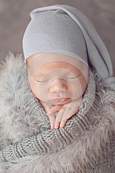 Newborn baby girl wrapped in gray with feathers