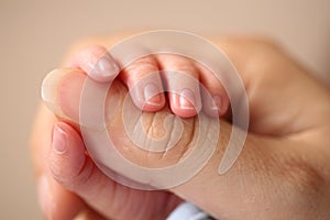 Newborn baby grasps his mother's hand