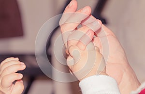 Newborn baby hand holding adult finger, maternity concept