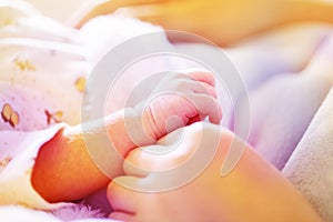 Newborn baby hand in mother`s hands with soft light blue blanket