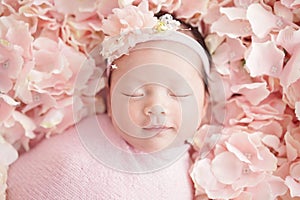 Newborn baby have a sweet dream with smile wearing a pink headband and swaddling with pink wrap