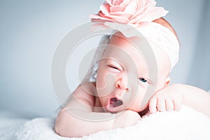 Newborn baby with headband on the head lying on blanket.