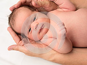 Newborn baby held by father's hands